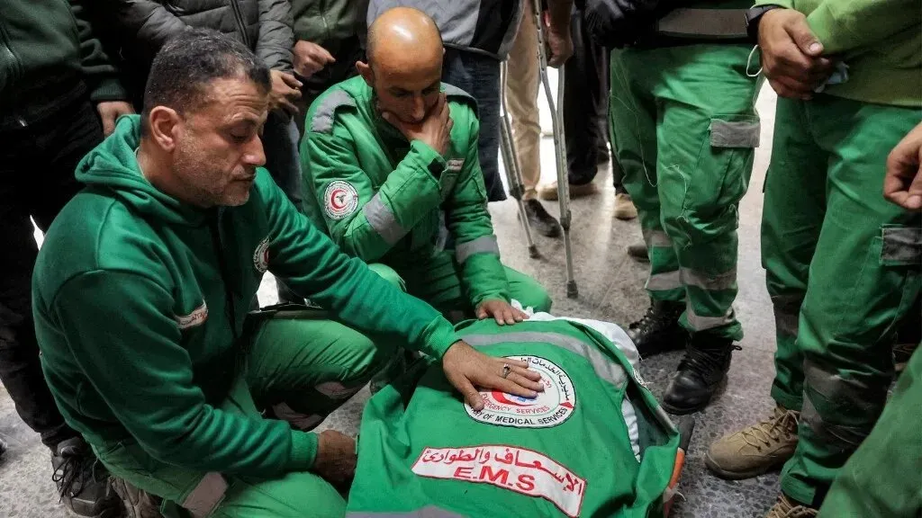 أفراد من خدمات الطوارئ الطبية الفلسطينية يعبرون عن حزنهم أثناء تأبين زملائهم الذين قُتلوا في غارة إسرائيلية، مع التركيز على فقدانهم.