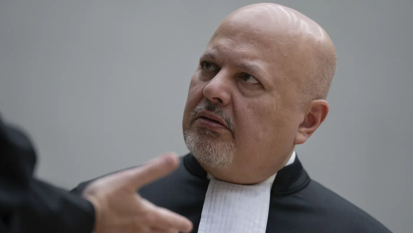 كاريم خان، المدعي العام للمحكمة الجنائية الدولية، يرتدي الزي الرسمي ويتلقى حديثاً جاداً، في سياق تصويت محتمل على إقالته بسبب قضايا سياسية وقانونية.