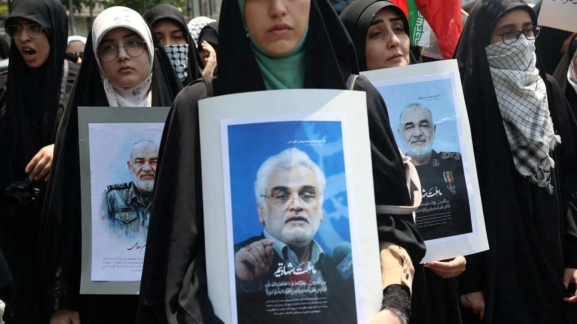 نساء يرتدين الحجاب يحملن لافتات تحمل صور شخصيات إيرانية، في مظاهرة تعبيرًا عن دعمهم، وسط أجواء من التوتر السياسي.