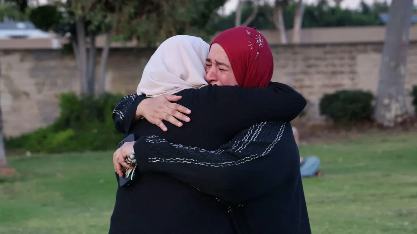 امرأتان ترتديان الحجاب تحتضنان بعضهما في حديقة، تعبيراً عن الحزن والدعم بعد حادثة إطلاق النار في سان دييغو.