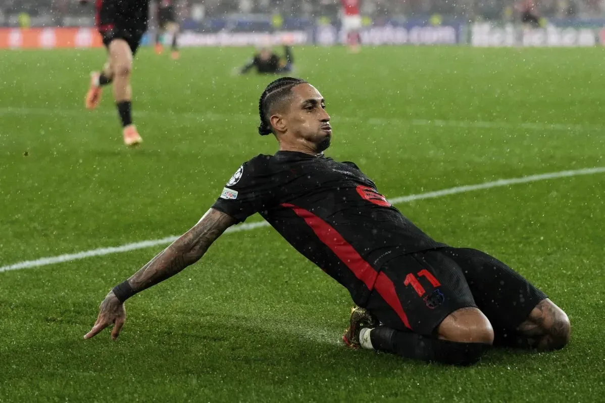 لاعب كرة قدم يشهر فرحته بعد تسجيل هدف، بينما تسقط الأمطار في ملعب المباراة، مما يعكس أجواء حماسية مثيرة في بطولة الأندية الأوروبية.