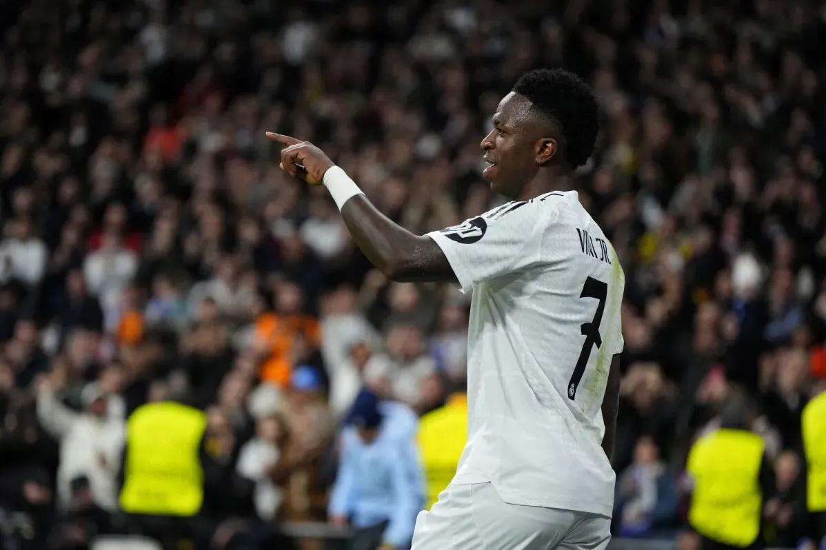 لاعب ريال مدريد، فينيسيوس جونيور، يحتفل بتسجيل هدف أثناء مباراة في دوري أبطال أوروبا، مع تفاعل جماهيري مثير خلفه.