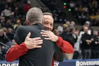 مدربان يتبادلان العناق قبل مباراة كرة السلة، مع تعبيرات ودية تعكس صداقتهما الطويلة وتاريخهما المشترك في التدريب.