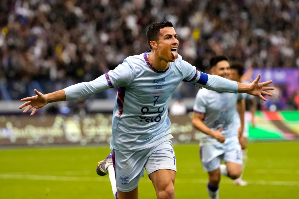 لاعب كرة قدم يحتفل بهدفه، مرتديًا قميصًا أزرق مع شعار الفريق، في أجواء حماسية خلال مباراة. يبرز أهمية كأس العالم 2026.