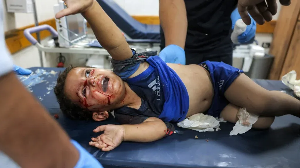 طفل فلسطيني مصاب ينقل في مستشفى بغزة، يعكس التقرير الأممي انتهاكات إسرائيلية ممنهجة بحق الأطفال الفلسطينيين في النزاع.