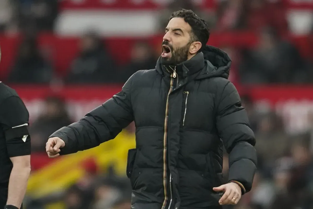 مدرب مانشستر يونايتد روبن أموريم يعبر عن استيائه خلال مباراة، مع خلفية مشجعي الفريق في ملعب أولد ترافورد.