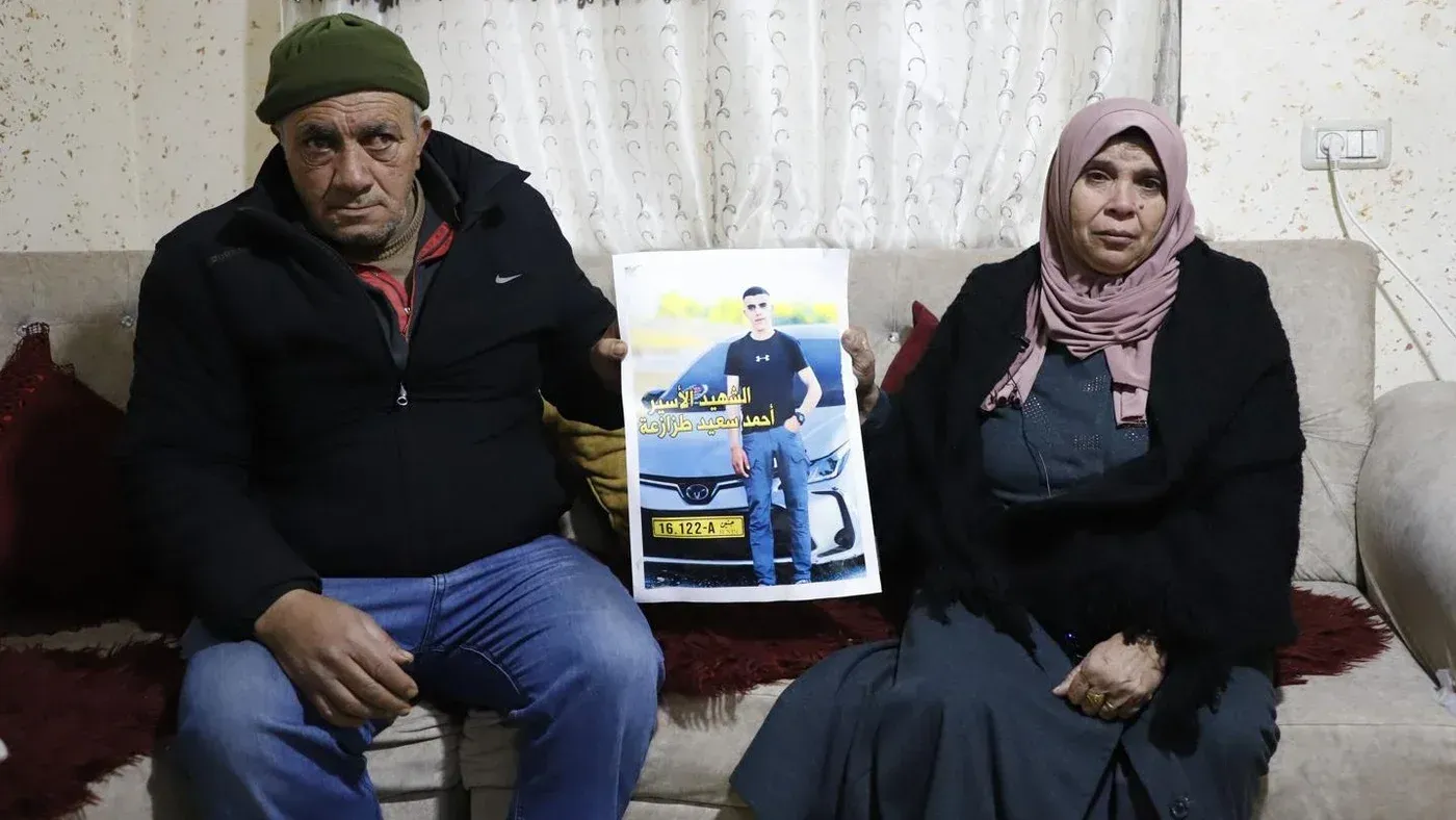 والدا أحمد تازا يجلسان في منزلهما، ممسكين بصورة لابنهما الراحل، معبرين عن حزنهما على وفاته في سجن مجدو.