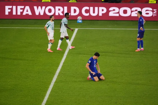 لاعب كرة قدم يجثو على أرض الملعب خلال مباراة في كأس العالم 2026 مع استخدام تقنية الكرة المتصلة لتحديد التسلل بدقة.