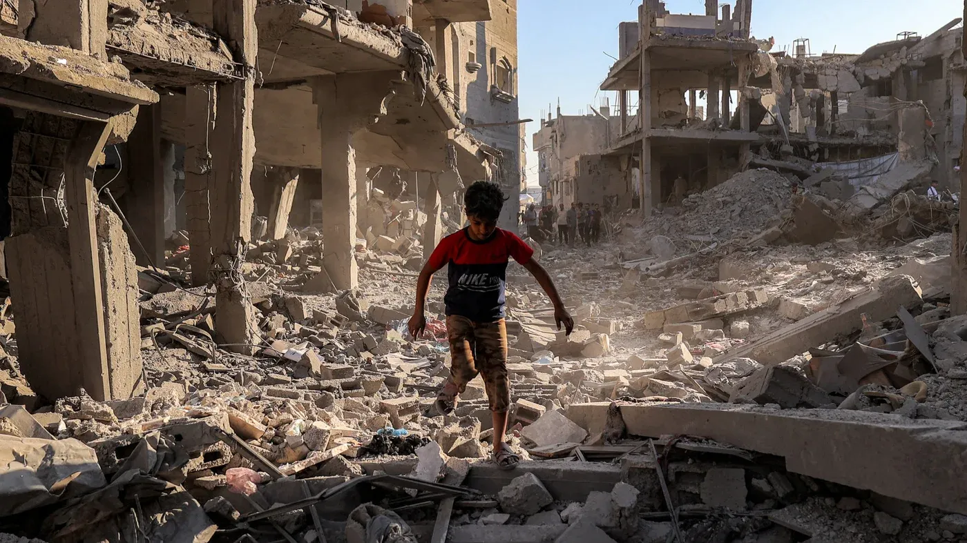 طفل يلعب بين أنقاض المباني المدمرة في غزة، حيث تكشف الصورة عن آثار الحرب والدمار الكبير الذي خلفته.