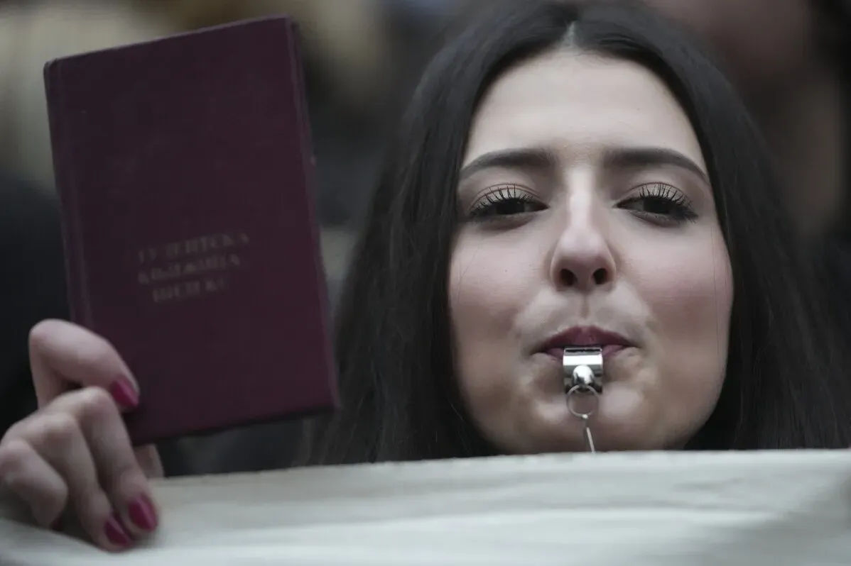 طالبة تحمل كتابًا وتنفخ في صفارة خلال مظاهرة أمام المحكمة العليا في بلغراد، تعبيرًا عن احتجاجات ضد انتهاكات حقوقها المدنية.