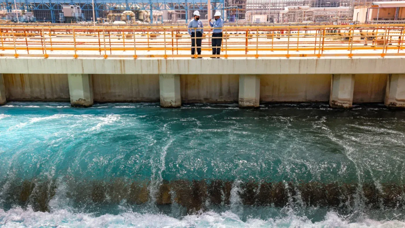 محطة لتحلية المياه في الخليج العربي، حيث يقف عمال بجانب المياه المتدفقة، تعكس أهمية البنية التحتية للمياه في المنطقة.
