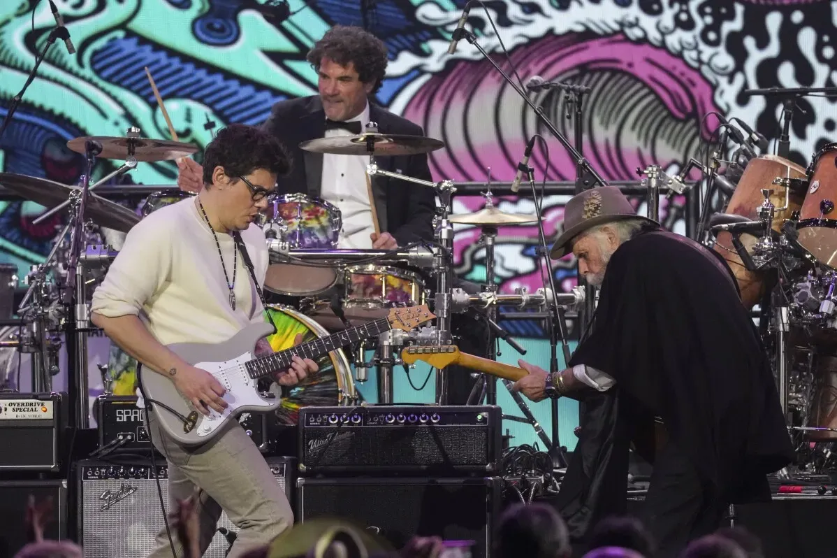 عازف الجيتار جون ماير وعازف الجيتار بوب وير أثناء الأداء في حفل تكريم فرقة Grateful Dead، مع خلفية ملونة تعكس روح الموسيقى.