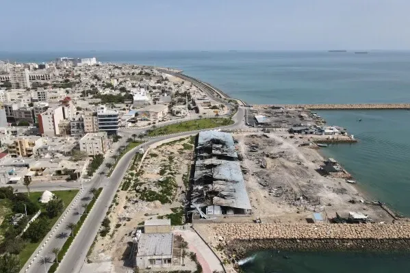 صورة جوية لميناء بالقرب من سواحل الخليج، تظهر المباني المتضررة والمياه الزرقاء، تعكس تأثير النزاع على حركة الملاحة البحرية.