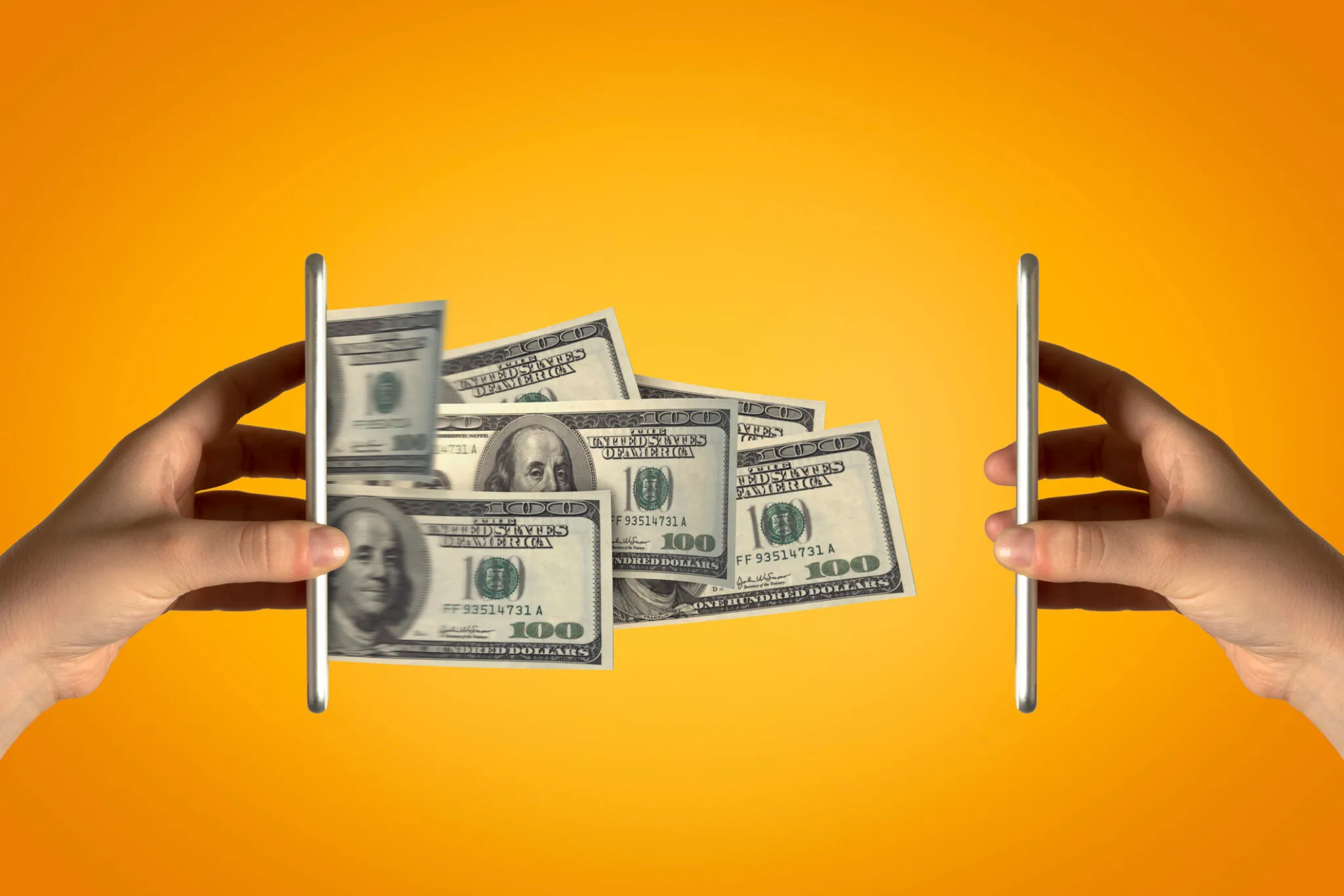 يدان تمسكان بهاتفين ذكيين يتدفق منهما أوراق نقدية من فئة 100 دولار، تعبيراً عن ارتفاع تكلفة تصنيع الهواتف الذكية بالكامل في أمريكا.