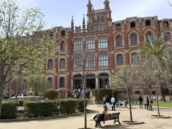 مبنى تاريخي في برشلونة، يتميز بتصميمه المعماري الفريد، حيث يتجمع الزوار في الحديقة المحيطة به.