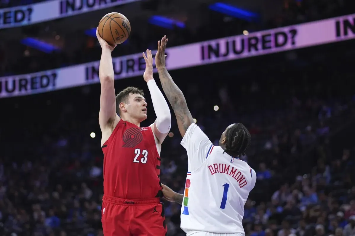 لاعب بورتلاند تريل بليزرز يقفز لتسديدة بينما يحاول لاعب فيلادلفيا 76ers الدفاع عنه في مباراة كرة سلة.