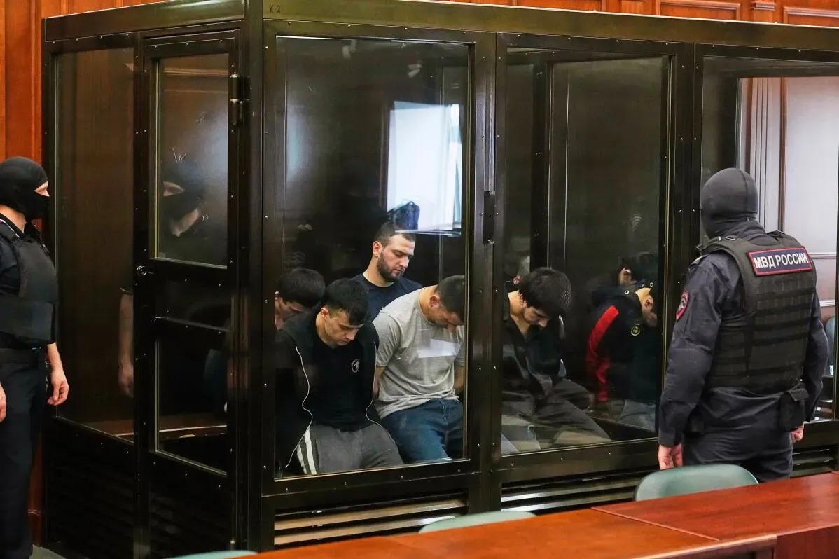 محاكمة 19 متهمًا في قاعة المحكمة بموسكو، حيث يظهر المتهمون داخل قفص زجاجي وسط إجراءات أمنية مشددة.