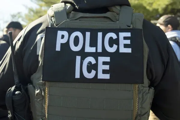 ظهر ضابط يرتدي سترة واقية تحمل كلمة "شرطة ICE" في سياق عمليات الترحيل للمهاجرين، وسط توترات قانونية حول حقوقهم.
