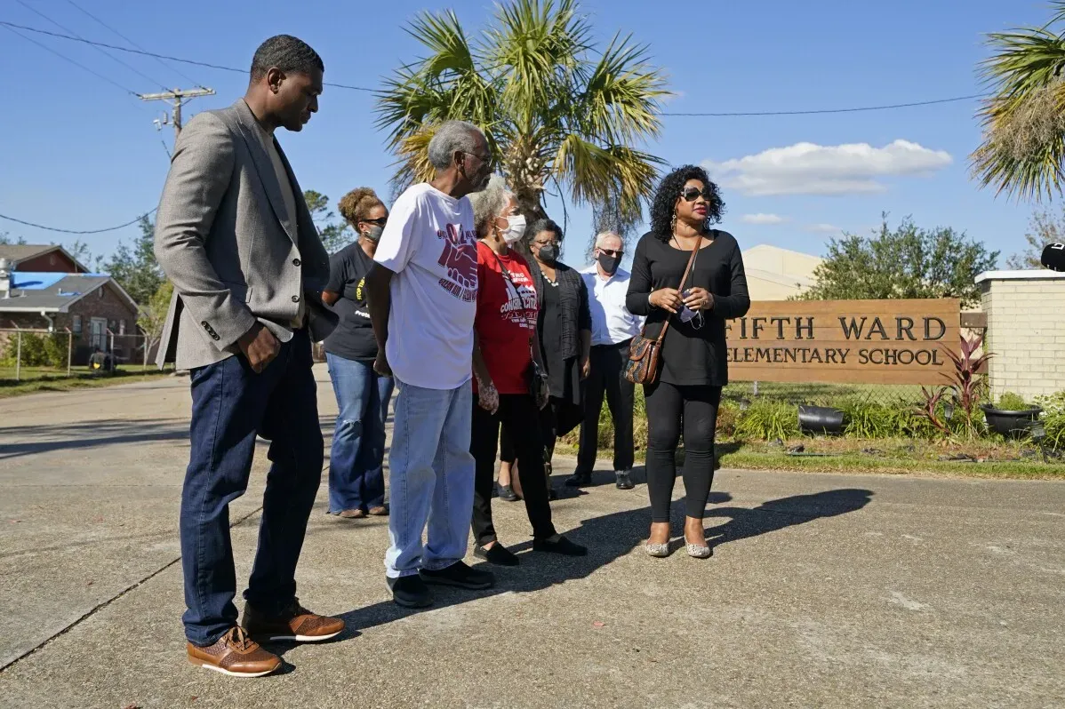 مجموعة من الأشخاص يقفون أمام مدرسة "Fifth Ward" الابتدائية في لويزيانا، حيث يتحدثون عن تأثير التلوث على المجتمع.