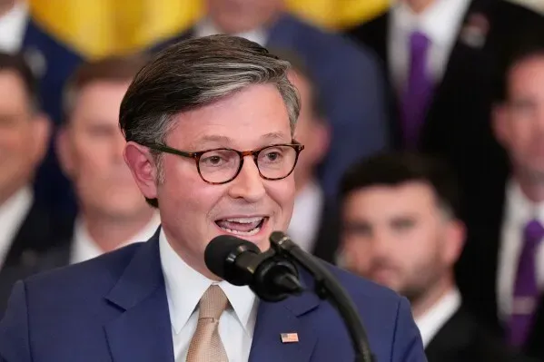 رجل يتحدث إلى ميكروفون خلال حدث رسمي، مع خلفية من الحضور في ملابس رسمية، يعكس أجواء سياسية في واشنطن.