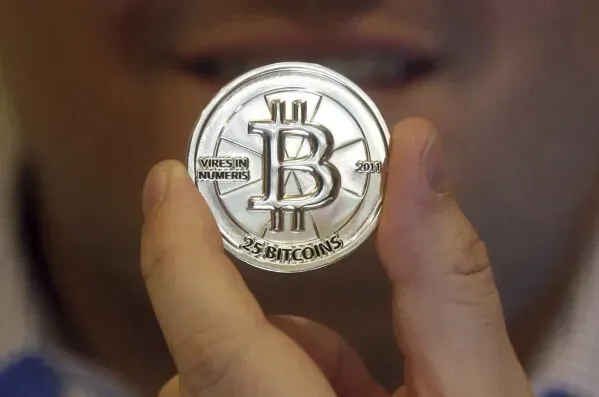 عملة بيتكوين معدنية تُظهر رمز العملة، مع شخص يحملها في يده، تعكس التوجهات الجديدة في استثمارات ترامب في العملات الرقمية.