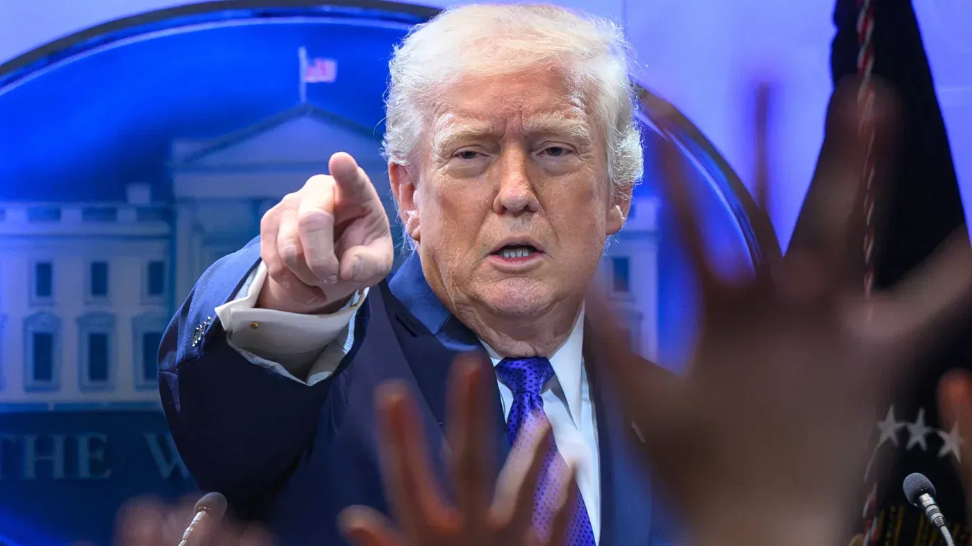 الرئيس الأمريكي دونالد ترامب يشير بيده أثناء مؤتمر صحفي، مع خلفية توضح شعار البيت الأبيض، وسط أجواء من التوترات السياسية حول إيران.