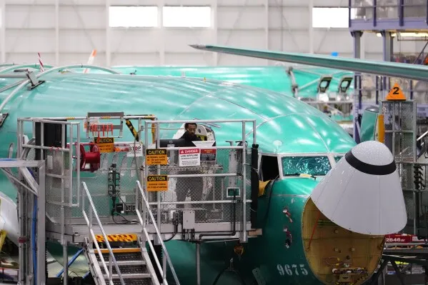 طائرة Boeing 737 Max قيد التجميع في المصنع، مع وجود عامل على المنصة، في سياق صفقة طائرات مع الصين تشمل 200 طائرة.