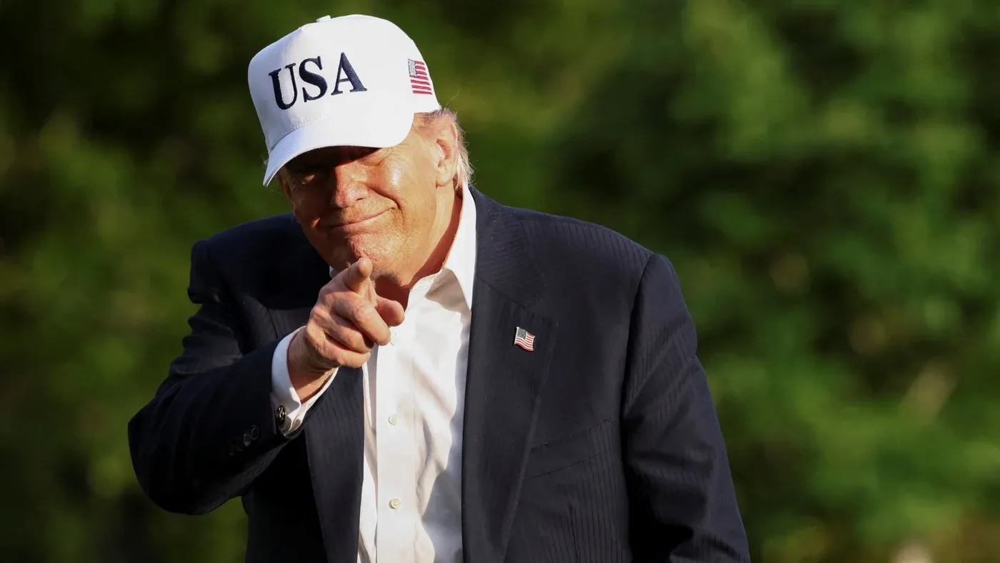 الرئيس الأمريكي دونالد ترامب يرتدي قبعة تحمل شعار "USA"، مبتسمًا ويشير بإصبعه، في سياق حديثه عن الدبلوماسية الخليجية وتأجيل الهجوم على إيران.