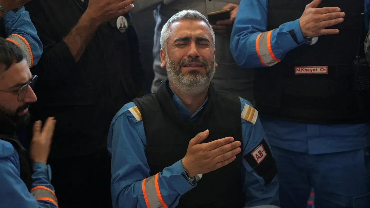 رجل يبكي بوضوح، محاط بأشخاص يرتدون زي العمل، في سياق إعلان الهدنة بين إسرائيل ولبنان. تعبيرات الحزن تعكس التوترات المستمرة.