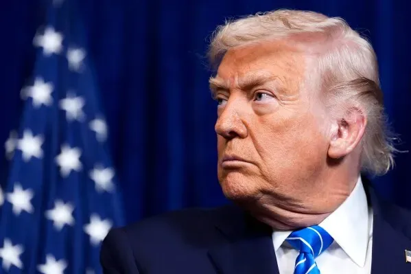 ترامب يستمع خلال مؤتمر صحفي، مع وجود علم الولايات المتحدة خلفه، حيث يتحدث عن المفاوضات بين أوكرانيا وروسيا.