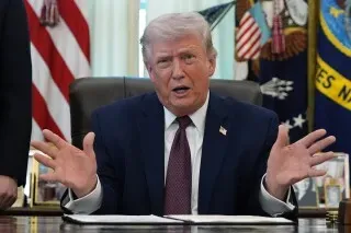 ترامب يتحدث خلال توقيع أمر تنفيذي لإنشاء قائمة بالناخبين المؤهلين، وسط أعلام أمريكية في المكتب البيضاوي.