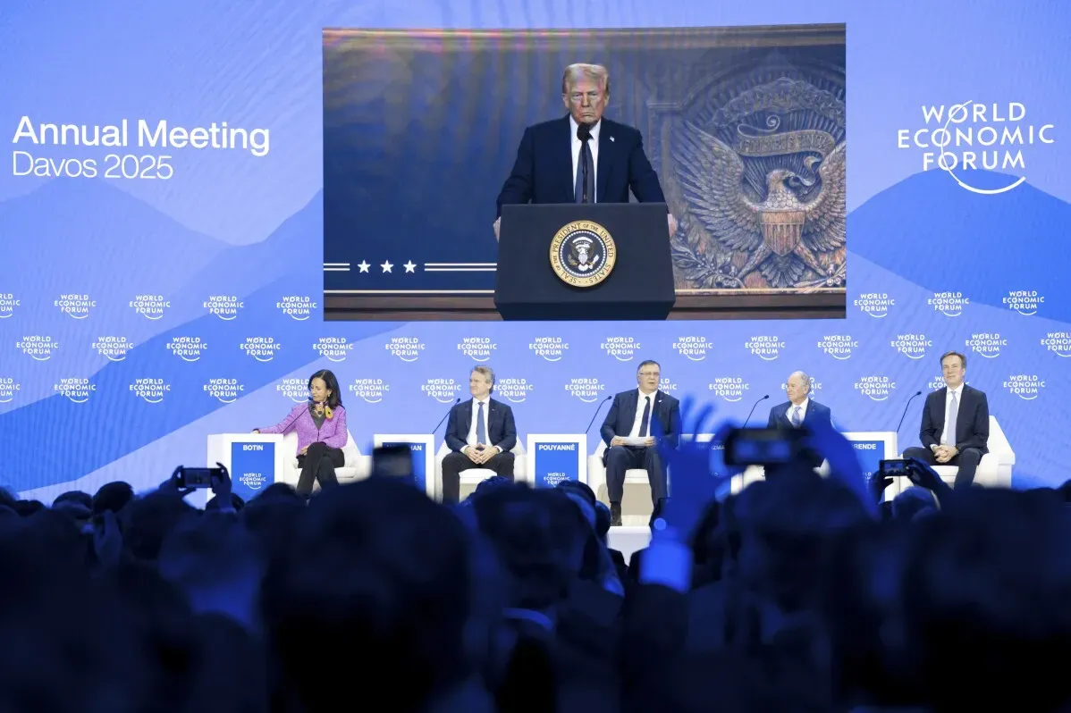 ترامب يتحدث في المنتدى الاقتصادي العالمي بدافوس 2025، مع عرض مباشر له على الشاشة، وسط حشد من الحضور.