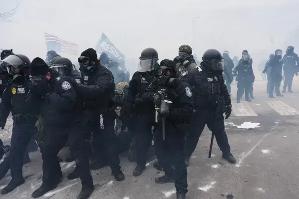 ضباط فيدراليون يرتدون ملابس مكافحة الشغب وأقنعة واقية من الغاز، يتقدمون وسط دخان كثيف أثناء الاحتجاجات في مينيابوليس.