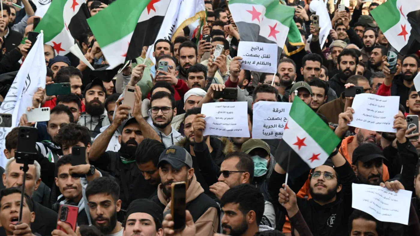 محتجون في سوريا يحملون لافتات وأعلامًا، يعبرون عن مطالبهم في تجمع حاشد لدعم الحرية والتغيير.