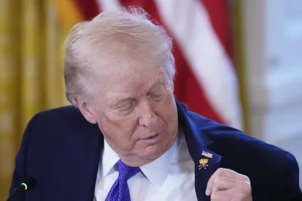 دونالد ترامب ينظر إلى دبوس يحمل صورته الكاريكاتورية على طية صدر سترته، خلال فعالية في البيت الأبيض لمناقشة صناعة الطاقة.