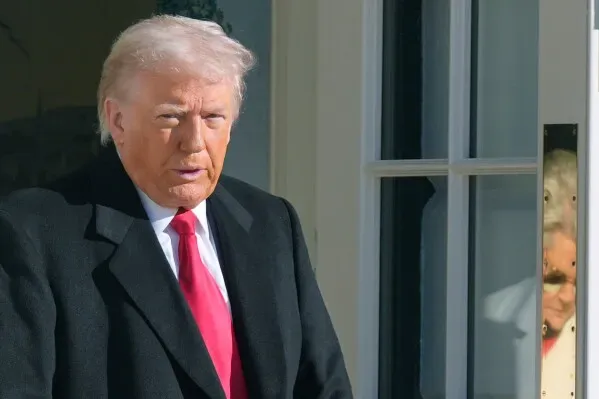 ترامب يغادر البيت الأبيض مرتديًا سترة سوداء ورابطة عنق حمراء، مع ظهور شخص آخر خلفه من خلال نافذة.