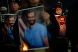 محتجون يحملون صورًا لشخص يُحتمل أن يكون ضحية، مع إضاءة الشموع، أثناء تظاهرة في مينيسوتا للتعبير عن الغضب من أعمال العنف.