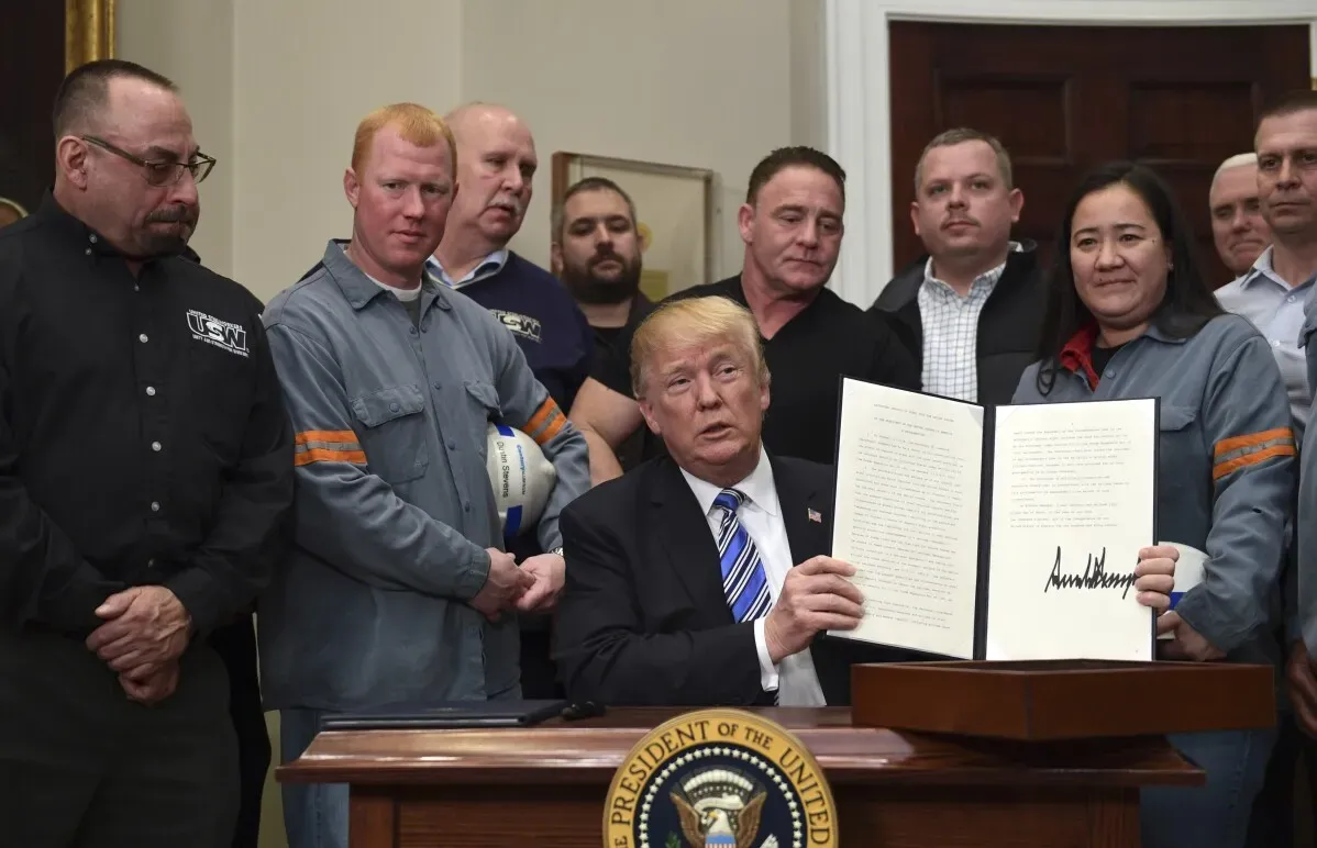 ترامب يوقع على وثيقة خلال حدث في البيت الأبيض، محاطًا بمجموعة من العمال، مع التركيز على تأثير التعريفات الجمركية على الاقتصاد.
