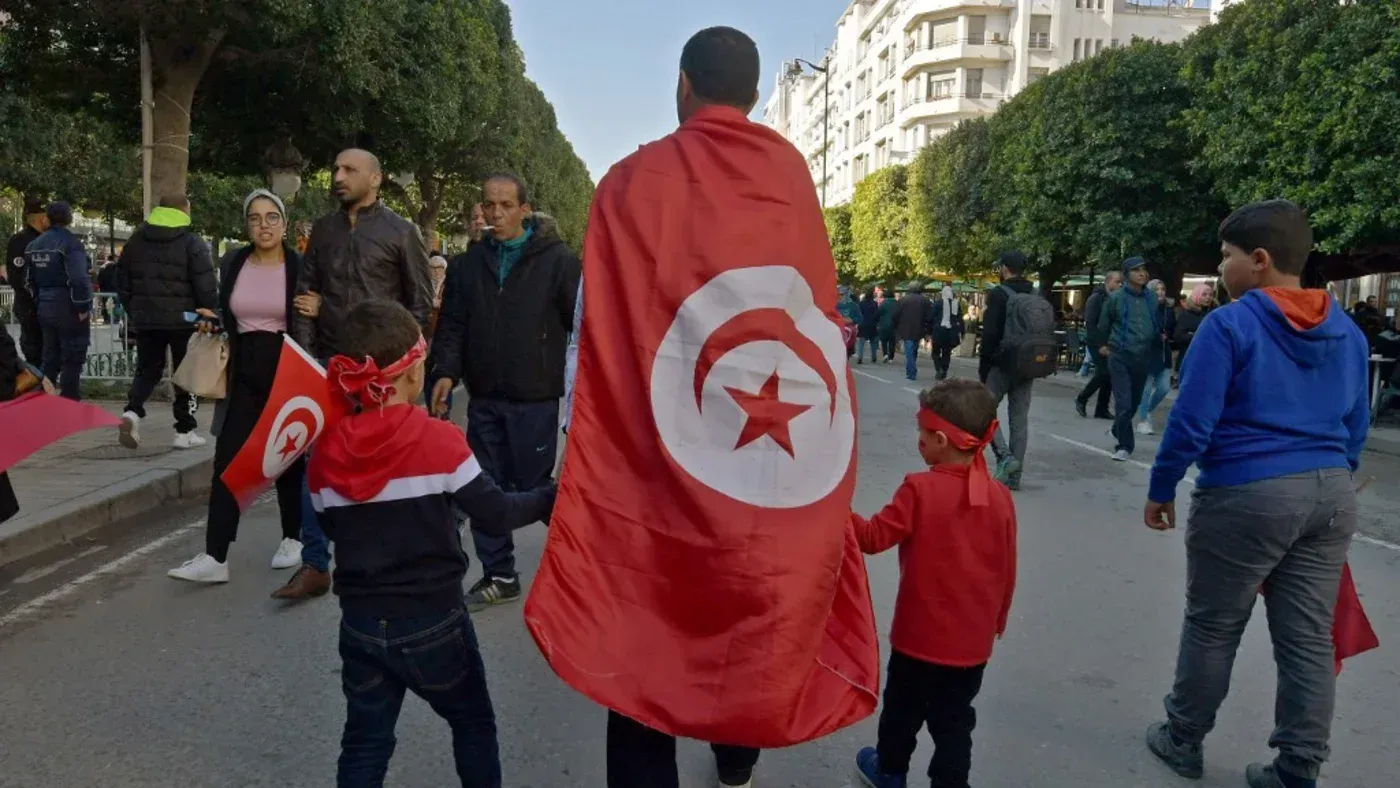 تجمع حشود في تونس للاحتفال بالذكرى الرابعة عشرة للثورة، حيث يحمل الأطفال الأعلام ويظهرون روح الأمل والتغيير.