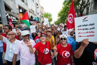مظاهرة في تونس تضم متظاهرين يحملون أعلام تونس وفلسطين ولافتات احتجاجية ضد الأحكام القضائية على المعارضين السياسيين.