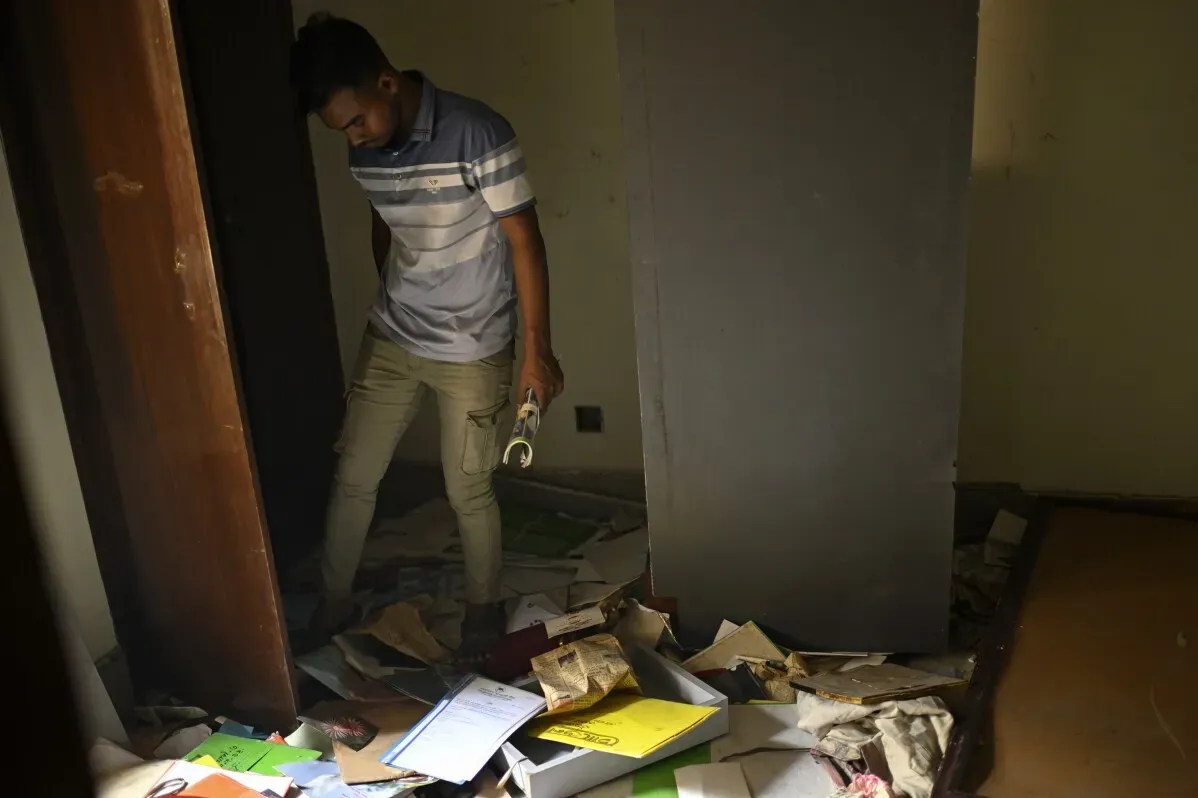 شخص يتفقد الفوضى في غرفة مدمرة، حيث تتناثر الأوراق والملفات على الأرض، في سياق الاحتجاجات ضد الحكومة المؤقتة في بنغلاديش.
