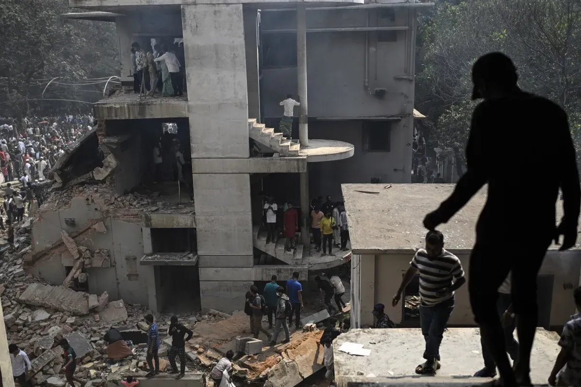 تظهر الصورة حشودًا من الناس في موقع بناء مهدوم في دكا، بنغلاديش، حيث تجمع المتظاهرون بعد أحداث عنف سياسي.
