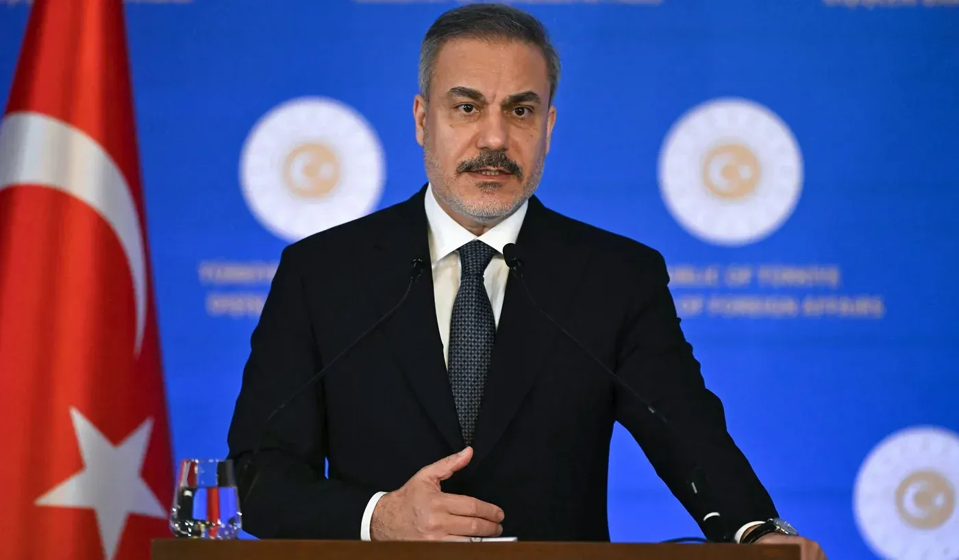 وزير الخارجية التركي هاكان فيدان يتحدث خلال مؤتمر صحفي في إسطنبول، مع وجود العلم التركي خلفه، حول التوترات في شمال سوريا.