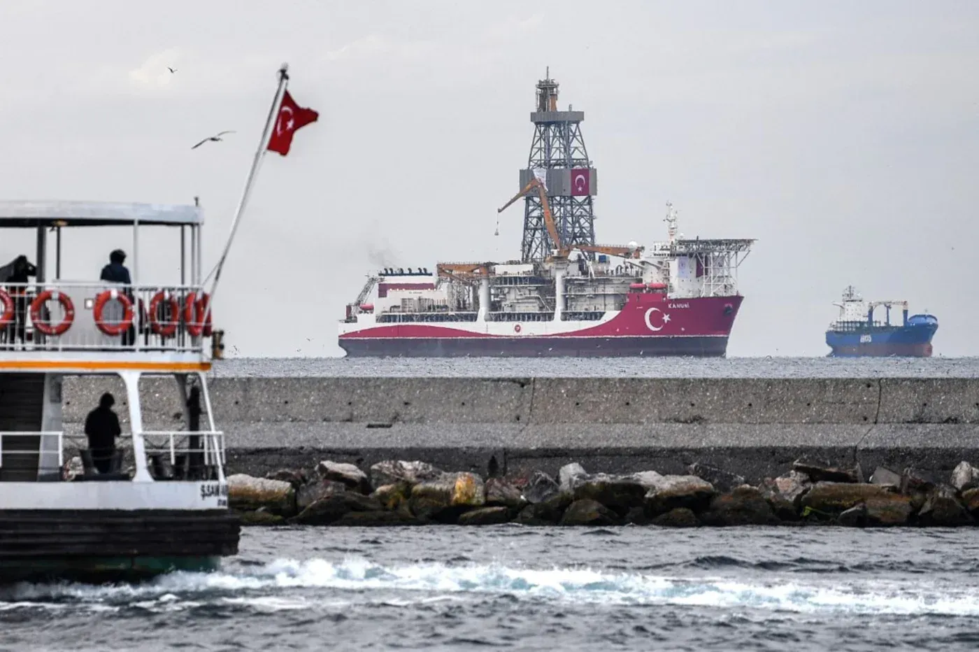سفينة تركية للتنقيب عن الطاقة تظهر في البحر، مع وجود قارب سياحي في المقدمة، تعكس التعاون التركي السوري في مجال الطاقة.