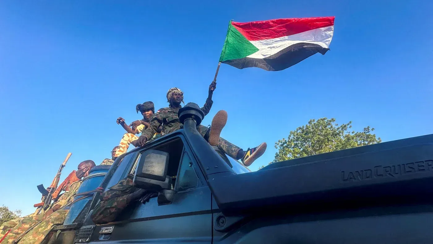 جنود سودانيون يرفعون علم السودان من فوق مركبة عسكرية، في سياق الصراع المستمر مع قوات الدعم السريع، مع تعزيز الدعم التركي للجيش.