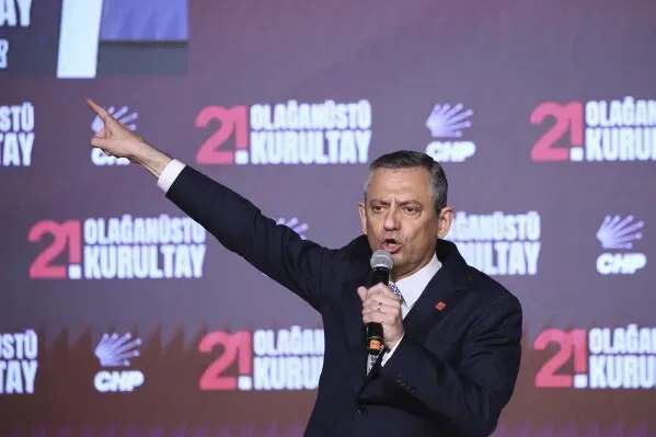 أوزغور أوزيل يتحدث في مؤتمر استثنائي لحزب الشعب الجمهوري بعد إعادة انتخابه، مع خلفية تحمل شعار الحزب وتاريخ المؤتمر.