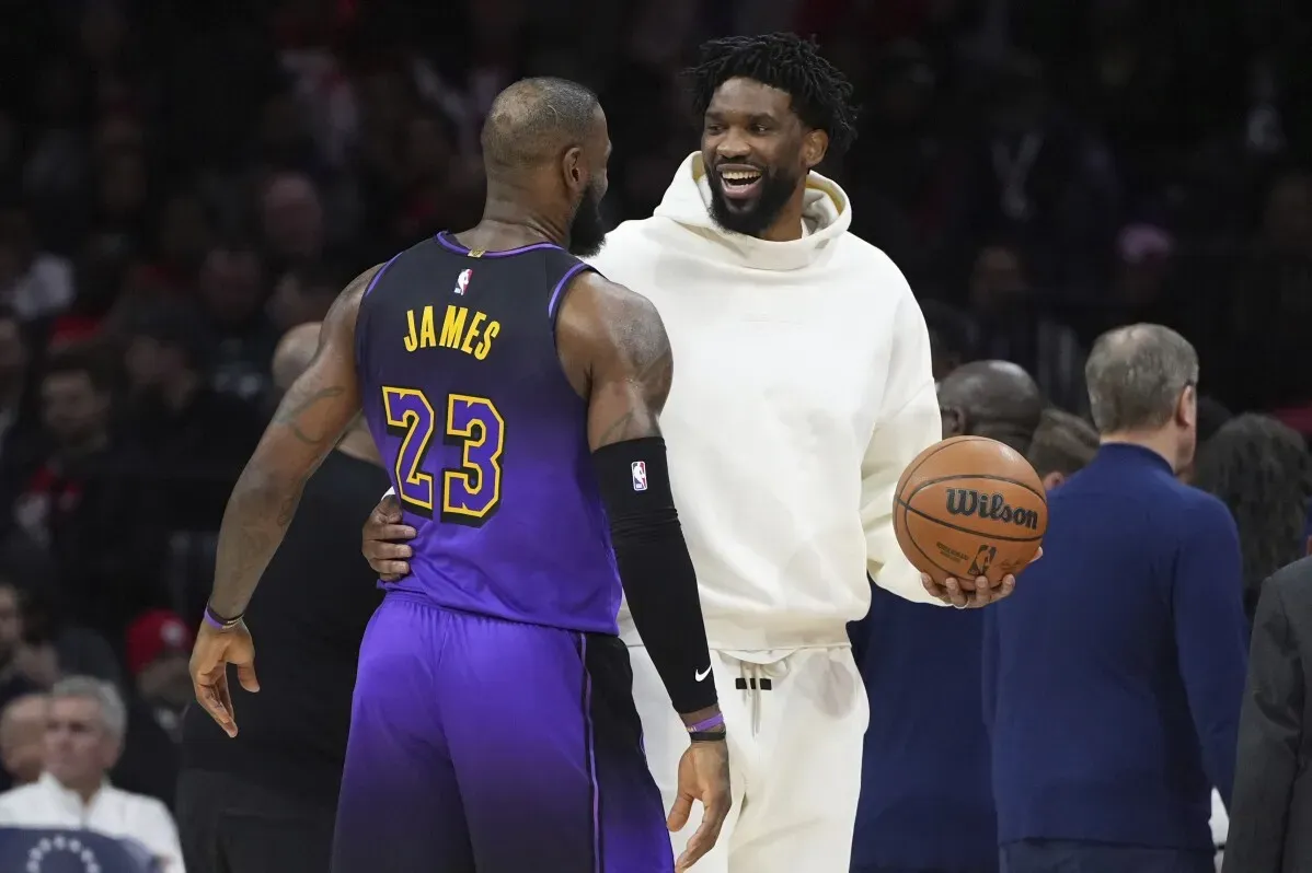 تيريس ماكسي مبتسم ويتحدث مع ليبرون جيمس قبل المباراة، حيث يحمل كرة سلة، مما يعكس أجواء الرياضة الحماسية.