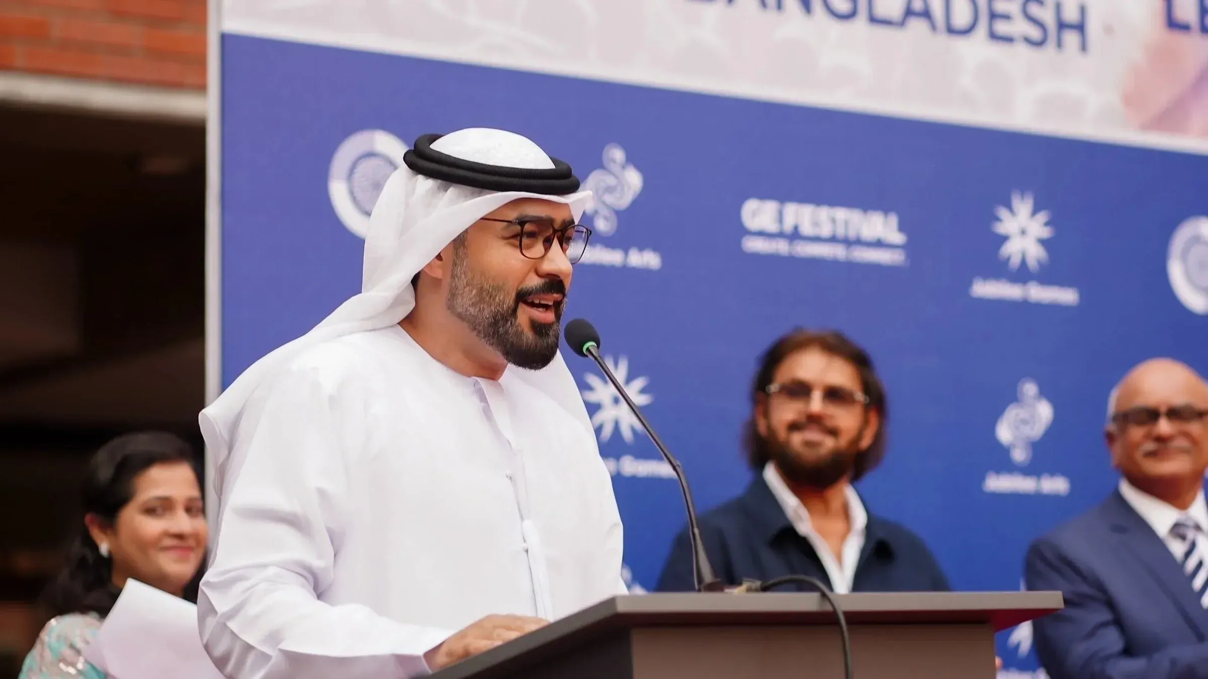 سفير الإمارات في بنغلاديش يتحدث خلال حدث رسمي، مع خلفية تحمل شعار المهرجان، مما يعكس العلاقات بين البلدين في مجال الطيران.