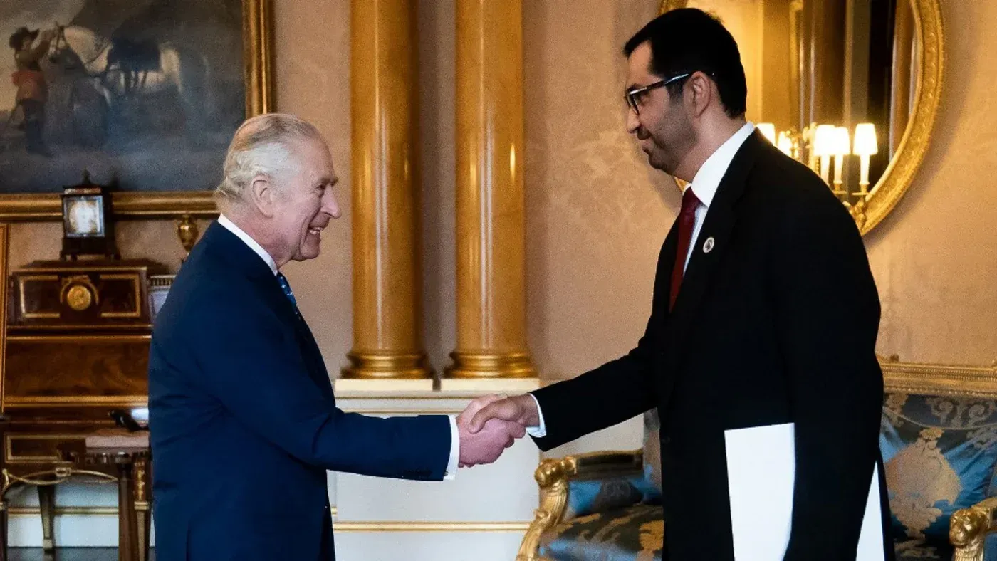 لقاء بين مسؤول إماراتي وملك المملكة المتحدة، حيث يتبادلان التحية في إطار مناقشات حول العلاقات الثنائية والتوترات السياسية.