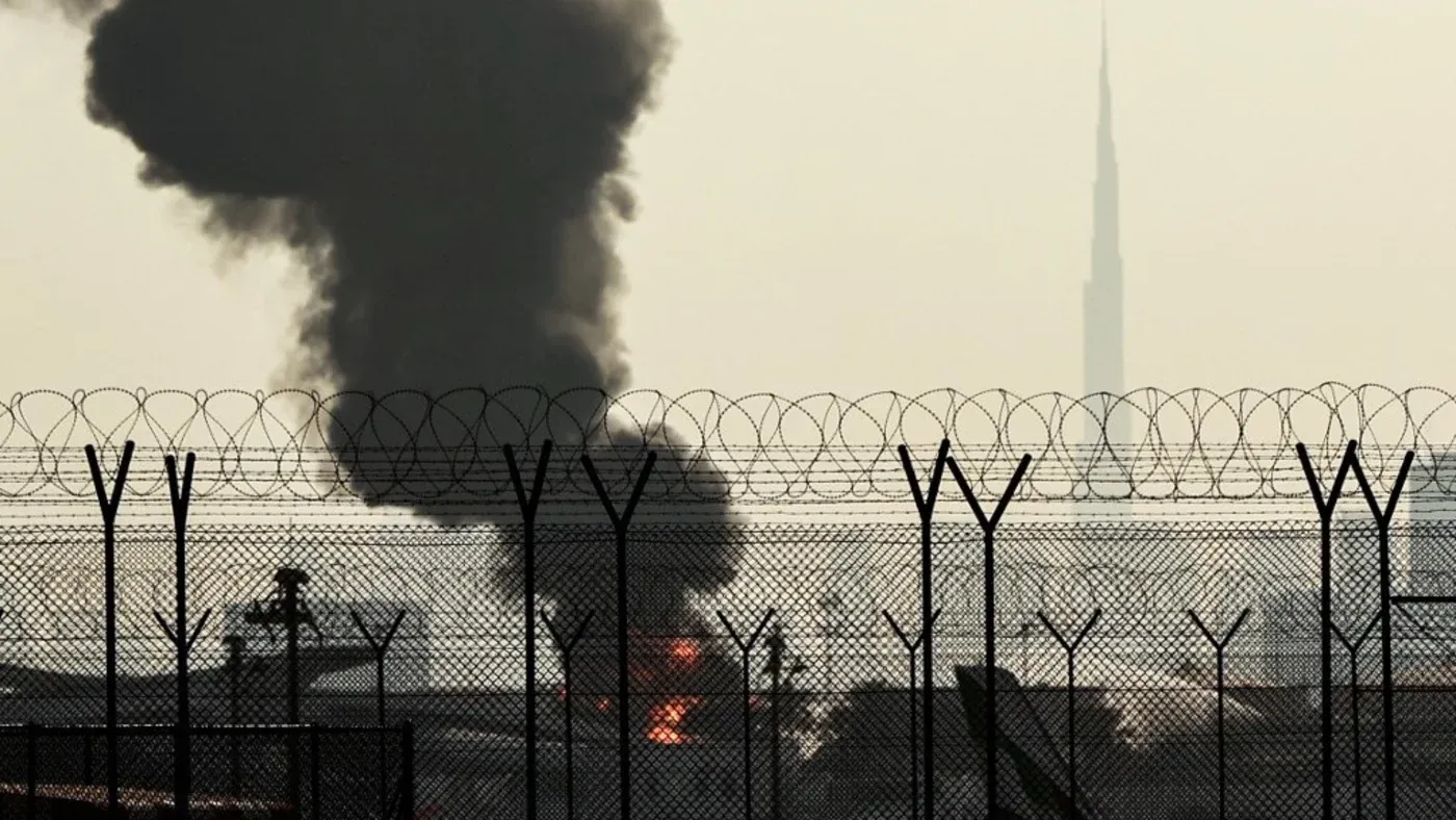 تصاعد الدخان من موقع استهداف مصفاة نفطية في إيران، مع ظهور برج خليفة في الخلفية، مما يعكس التوترات العسكرية بين الإمارات وإيران.